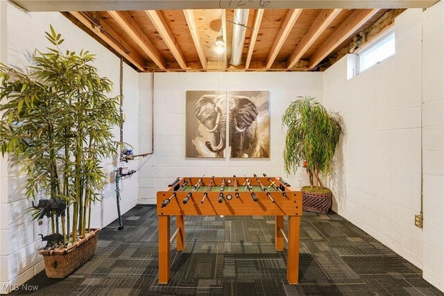 playroom featuring dark colored carpet and concrete block wall