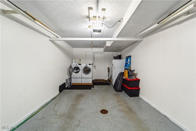 garage with baseboards, a garage door opener, freestanding refrigerator, and independent washer and dryer
