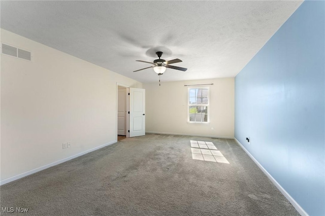 carpeted empty room featuring baseboards, ceiling fan, a textured ceiling, and visible vents