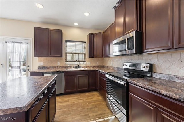 kitchen with a sink, light wood-style flooring, appliances with stainless steel finishes, and decorative backsplash