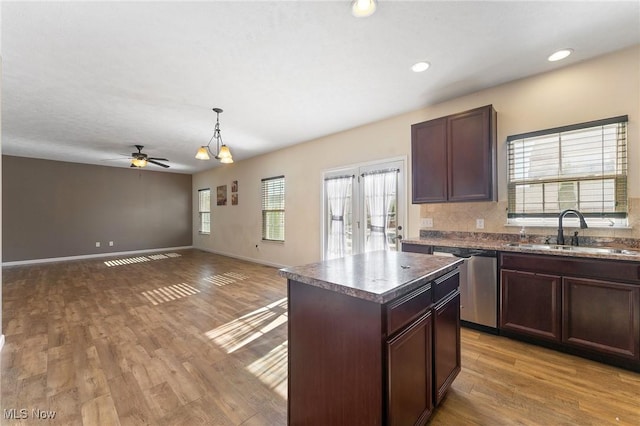 kitchen with ceiling fan, a sink, light wood-style floors, dishwasher, and a center island