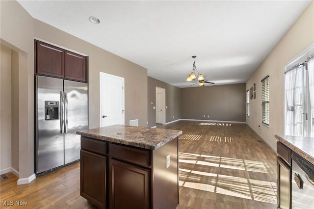 kitchen featuring dark brown cabinetry, appliances with stainless steel finishes, wood finished floors, baseboards, and a notable chandelier