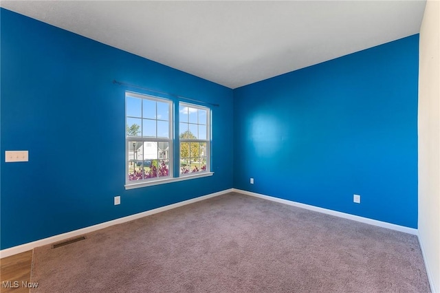empty room with baseboards, visible vents, and carpet