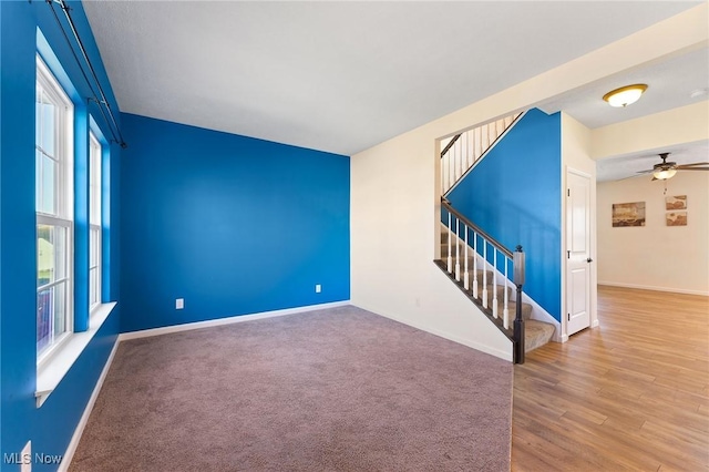 spare room with baseboards, a ceiling fan, stairs, and wood finished floors