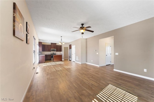 unfurnished living room with baseboards, wood finished floors, and ceiling fan with notable chandelier