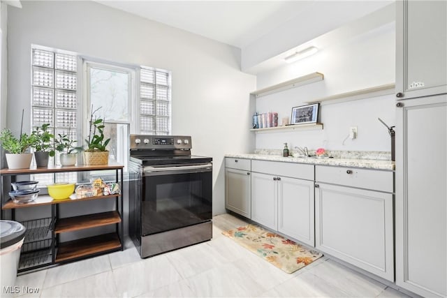 kitchen with a sink, open shelves, stainless steel electric range, and light stone countertops