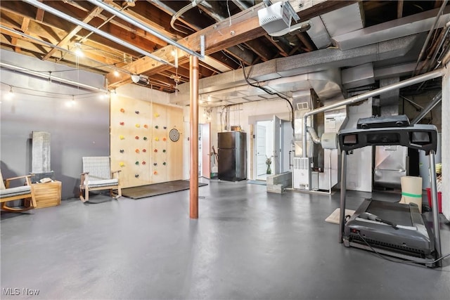 unfinished basement with freestanding refrigerator, visible vents, and heating unit