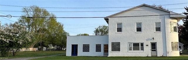 exterior space with stucco siding and a yard
