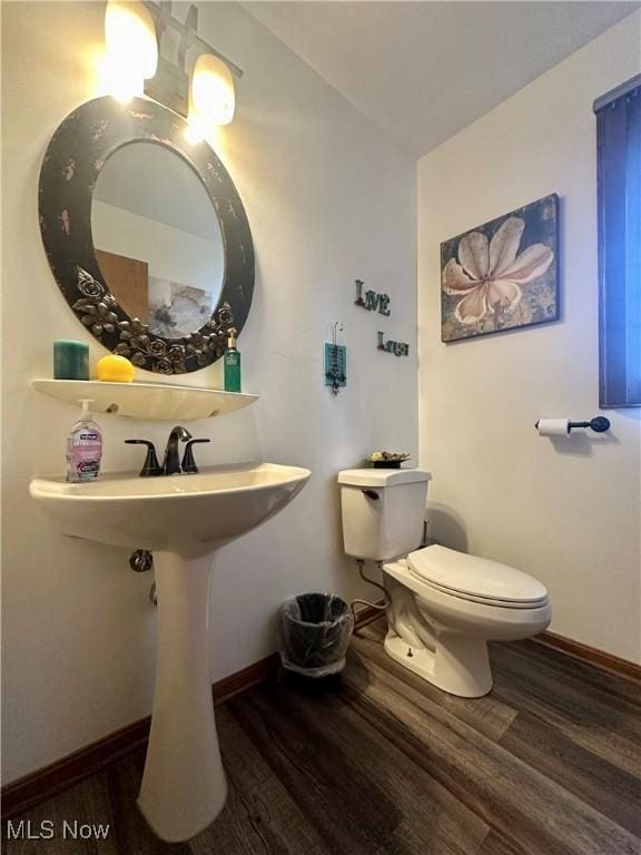 half bath with baseboards, wood finished floors, and toilet