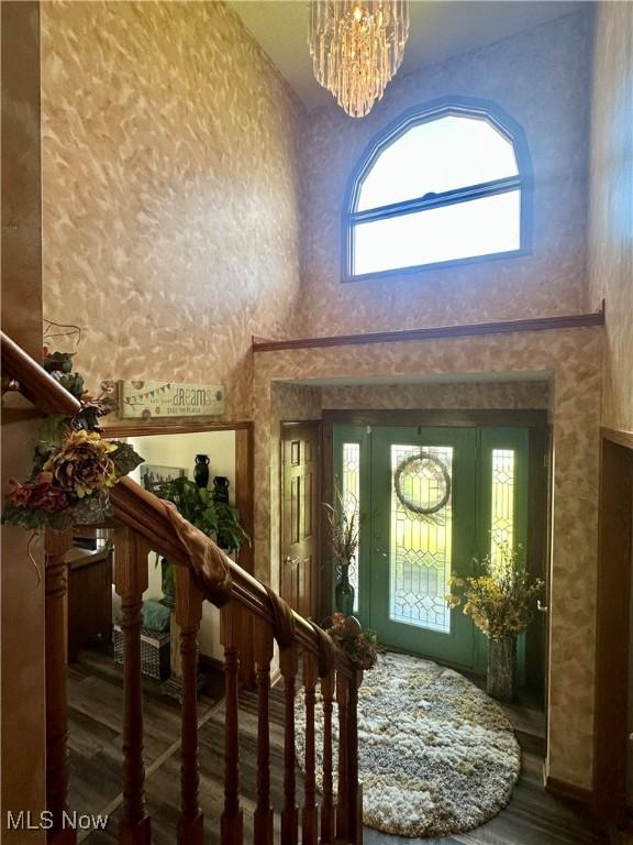 entryway with an inviting chandelier, a high ceiling, stairs, and wood finished floors