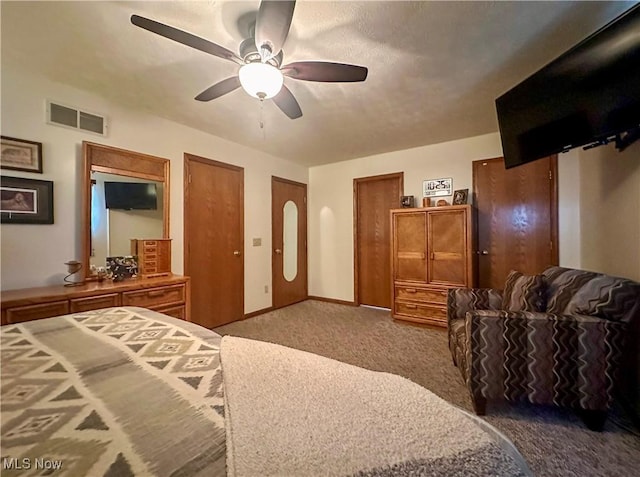 carpeted bedroom with visible vents, a ceiling fan, multiple closets, and baseboards