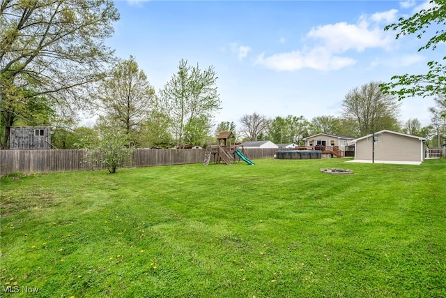 view of yard with a fenced backyard, a playground, and an outdoor fire pit