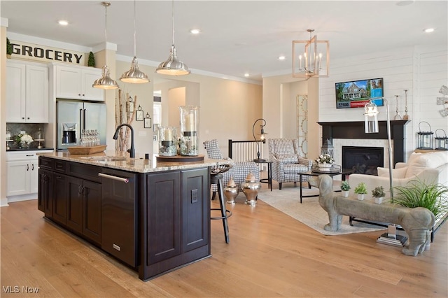 kitchen with a sink, light wood-type flooring, high end fridge, and white cabinetry