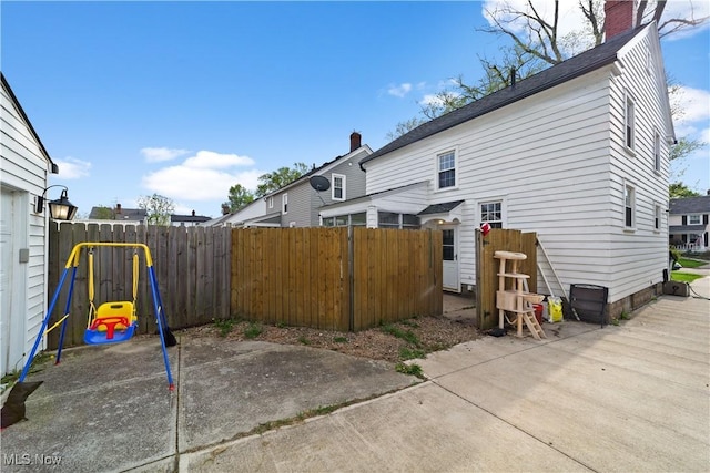 view of side of home featuring fence, a chimney, and a patio area