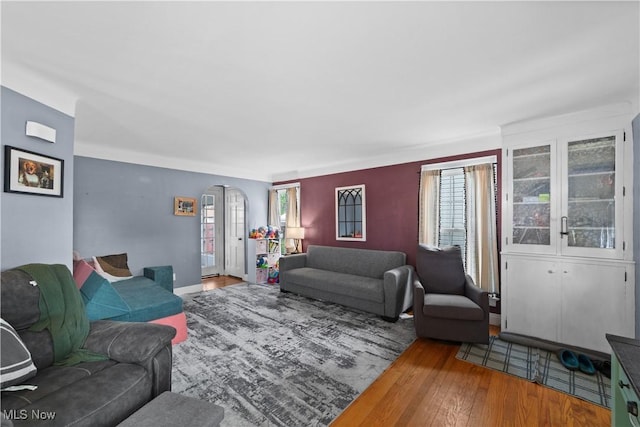 living area featuring baseboards, arched walkways, a wealth of natural light, and hardwood / wood-style flooring