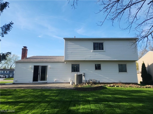 rear view of property featuring a yard, a patio, a chimney, and central AC unit