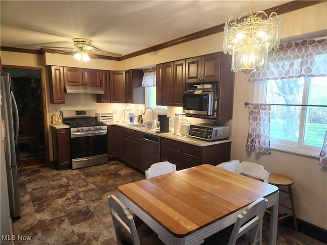 kitchen featuring a sink, light countertops, ceiling fan with notable chandelier, stainless steel appliances, and under cabinet range hood