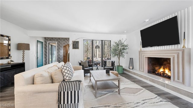 living area with baseboards, a large fireplace, and wood finished floors