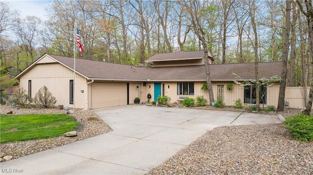view of front of home featuring roof with shingles, an attached garage, and driveway