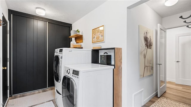 laundry area featuring baseboards, laundry area, light wood-type flooring, and washing machine and clothes dryer