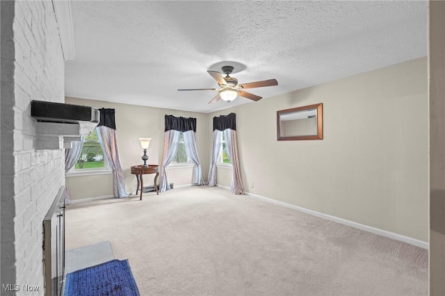 unfurnished room featuring baseboards, a ceiling fan, a textured ceiling, and a fireplace
