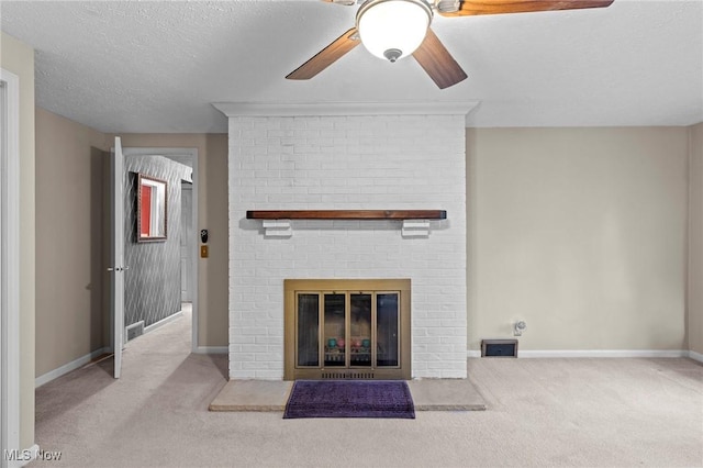 unfurnished living room featuring ceiling fan, carpet floors, a brick fireplace, a textured ceiling, and baseboards