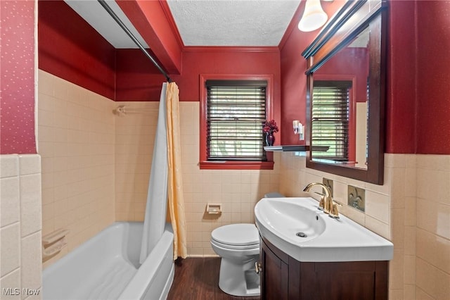 bathroom with tile walls, a wainscoted wall, toilet, and wood finished floors