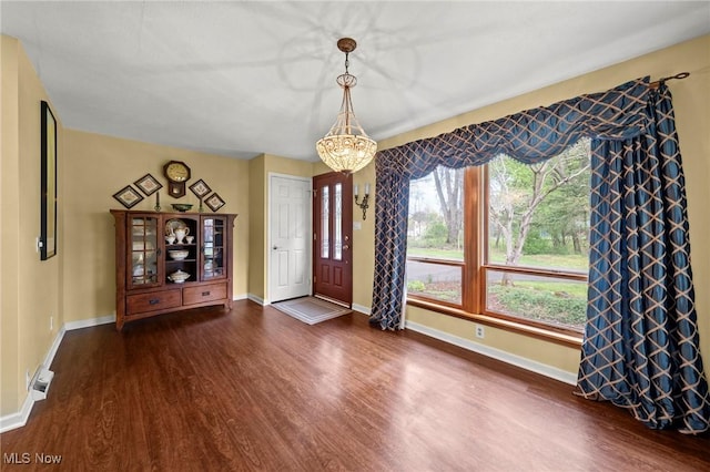 entrance foyer with baseboards, dark wood finished floors, and an inviting chandelier
