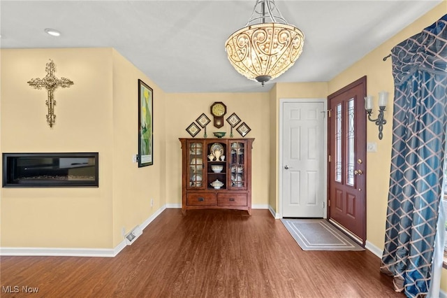 foyer with an inviting chandelier, baseboards, wood finished floors, and visible vents