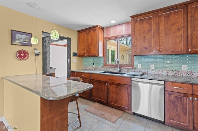 kitchen with stainless steel dishwasher, decorative backsplash, a breakfast bar area, light stone counters, and a sink