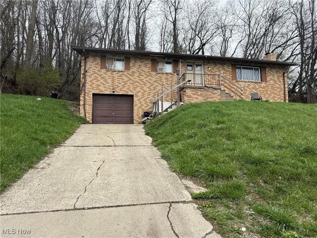 ranch-style home featuring an attached garage, concrete driveway, a front yard, and brick siding