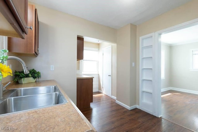kitchen featuring dark wood-style flooring, brown cabinets, a sink, light countertops, and a wealth of natural light