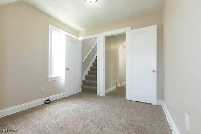 spare room with carpet flooring, baseboards, and stairway