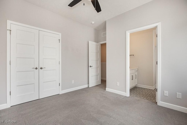 unfurnished bedroom featuring baseboards, ensuite bathroom, a closet, and light colored carpet