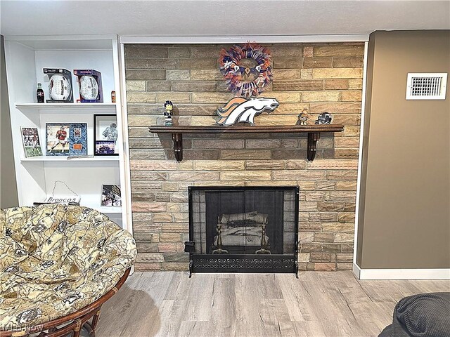 interior details with a large fireplace, wood finished floors, and visible vents