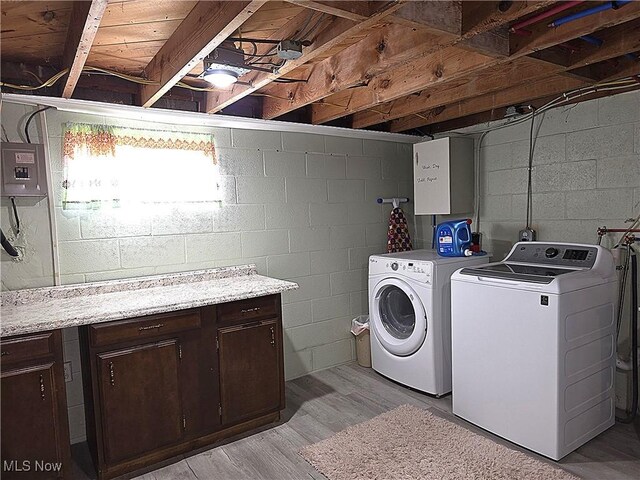 laundry area featuring electric panel, washing machine and dryer, light wood finished floors, and cabinet space