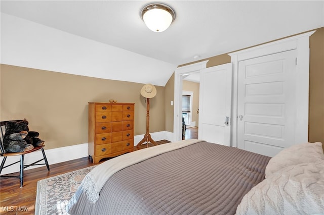 bedroom featuring baseboards, vaulted ceiling, and wood finished floors