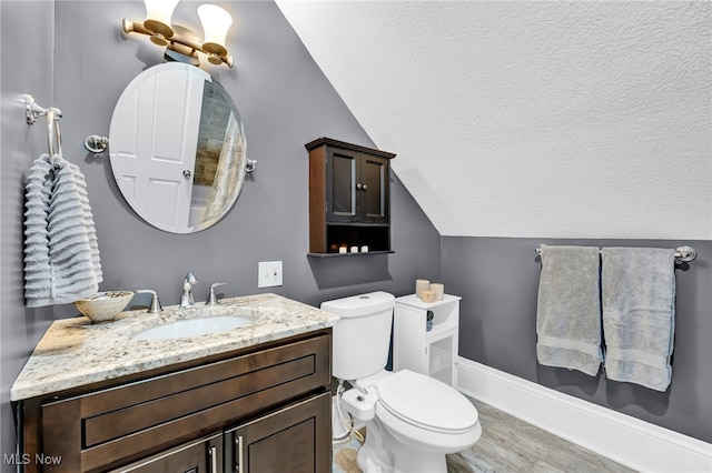 bathroom with vanity, toilet, a textured ceiling, wood finished floors, and vaulted ceiling