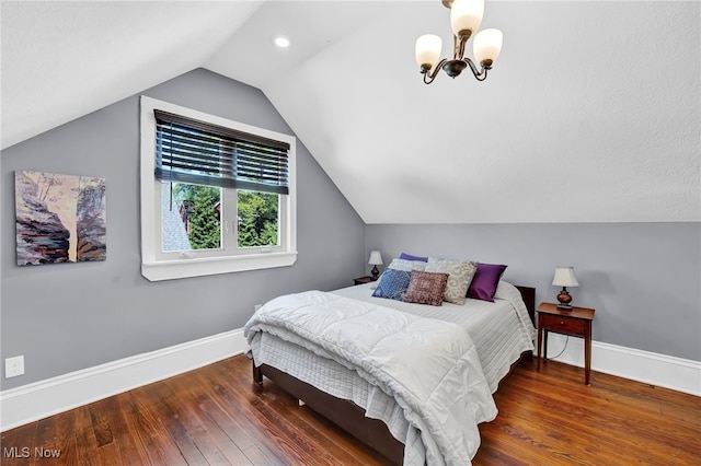 bedroom featuring baseboards, lofted ceiling, wood finished floors, and a chandelier