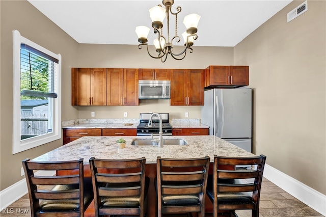 kitchen with visible vents, freestanding refrigerator, stainless steel microwave, a chandelier, and a sink