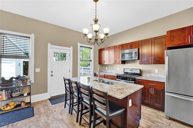 kitchen with light wood-type flooring, a sink, an inviting chandelier, a breakfast bar, and stainless steel appliances