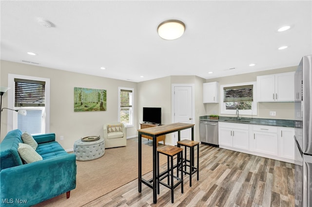 kitchen featuring white cabinets, open floor plan, appliances with stainless steel finishes, and a sink