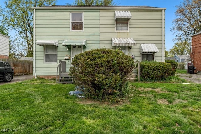 rear view of house with fence and a yard