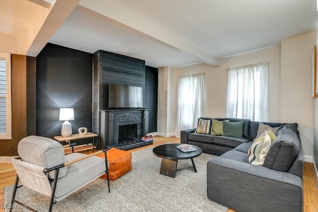 living area featuring beamed ceiling, baseboards, and wood finished floors