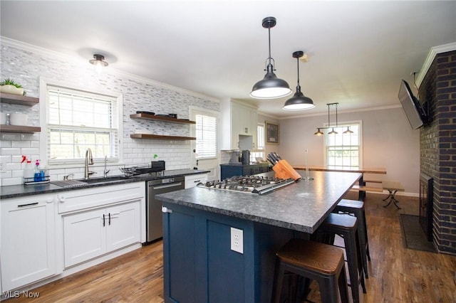 kitchen featuring open shelves, a healthy amount of sunlight, dark countertops, a sink, and appliances with stainless steel finishes