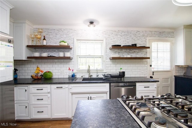 kitchen with open shelves, appliances with stainless steel finishes, dark countertops, and a sink