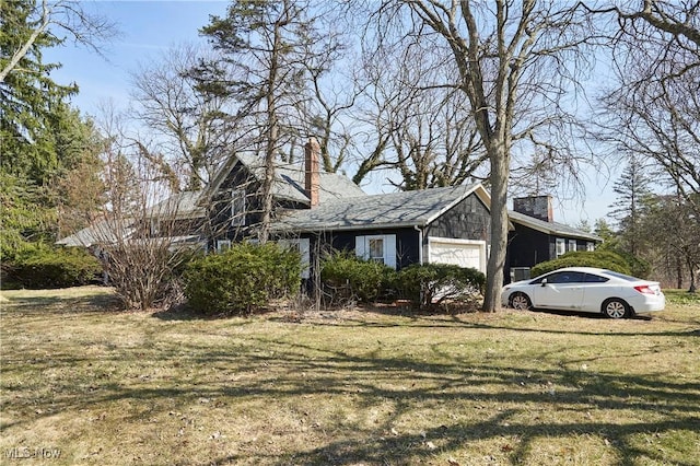 view of side of home featuring an attached garage, a lawn, and a chimney