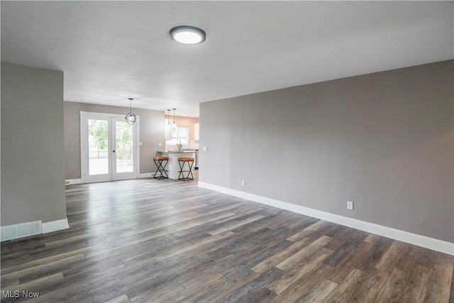 unfurnished living room with baseboards, dark wood finished floors, and visible vents