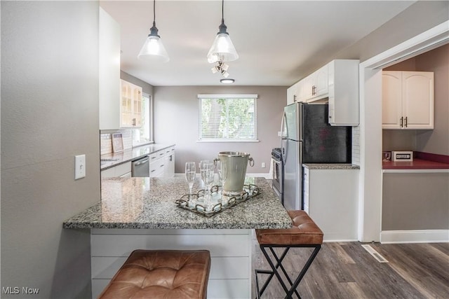 kitchen featuring dark wood-style flooring, light stone counters, a kitchen breakfast bar, white cabinetry, and stainless steel appliances
