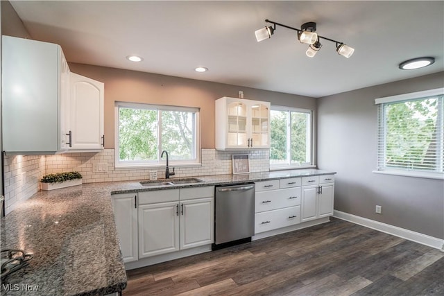 kitchen featuring a sink, dark stone countertops, dishwasher, and a wealth of natural light